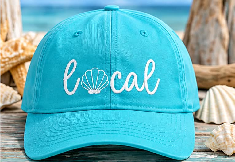 Turquoise ball cap embroidered with the word local, with a seashell for the letter o