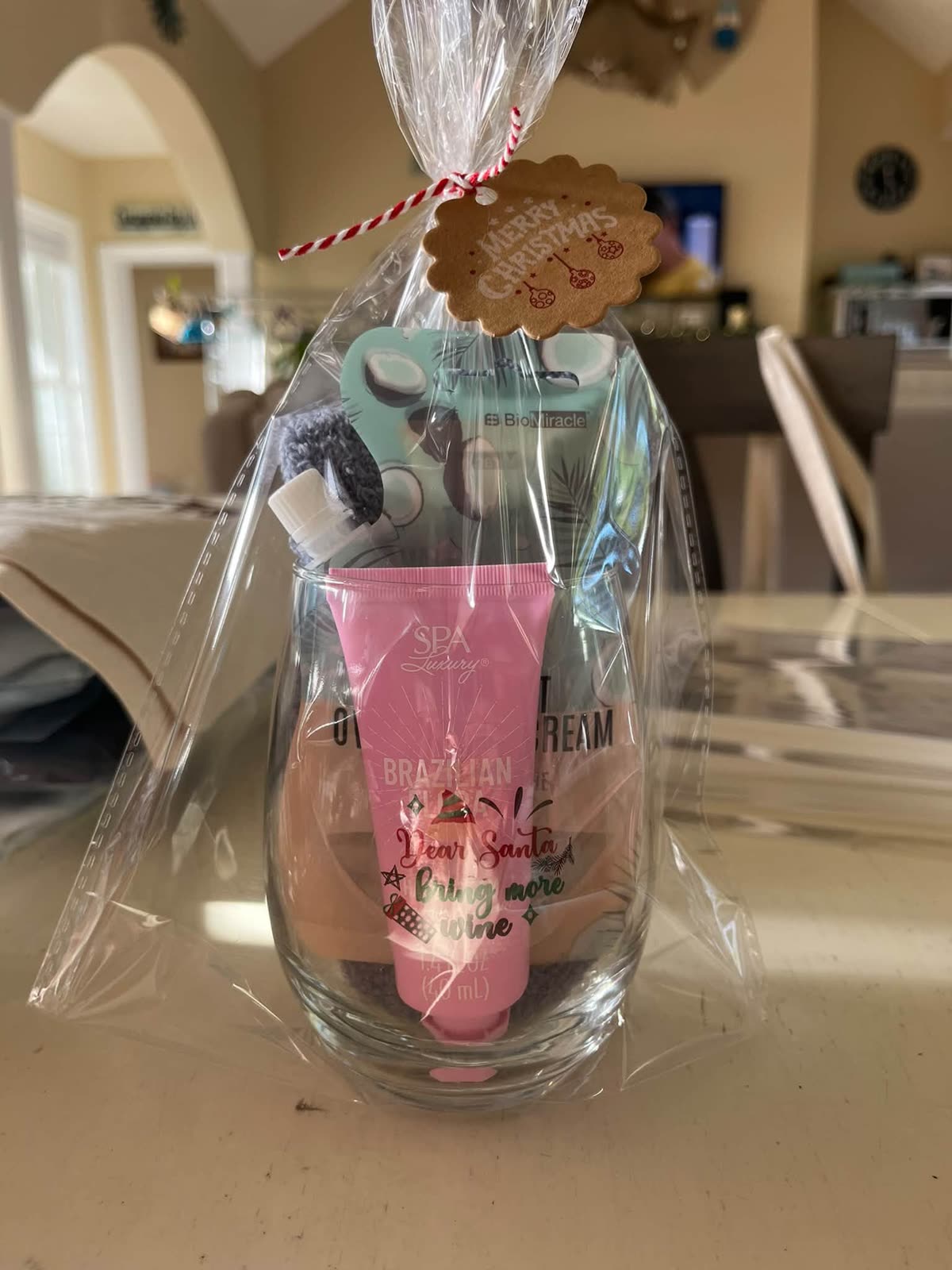 Wine glass spa gift set wrapped in cellophane with a red and white ribbon and Merry Christmas tag