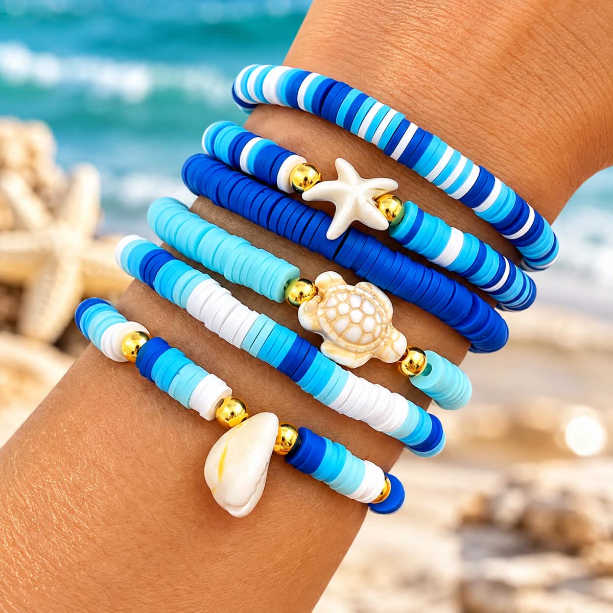 Wrist stacked with blue and white clay bead bracelets with starfish, sea turtle and cowrie shell charms