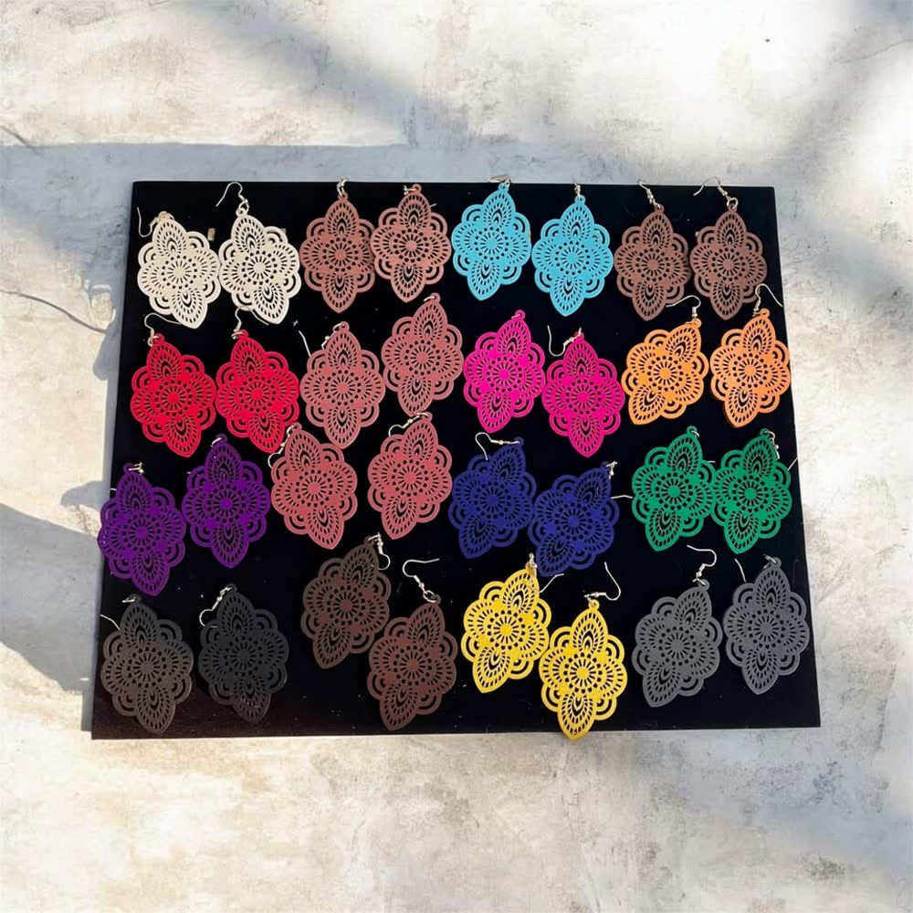 Lacy filigree drop earrings in many colors laid out on a black board