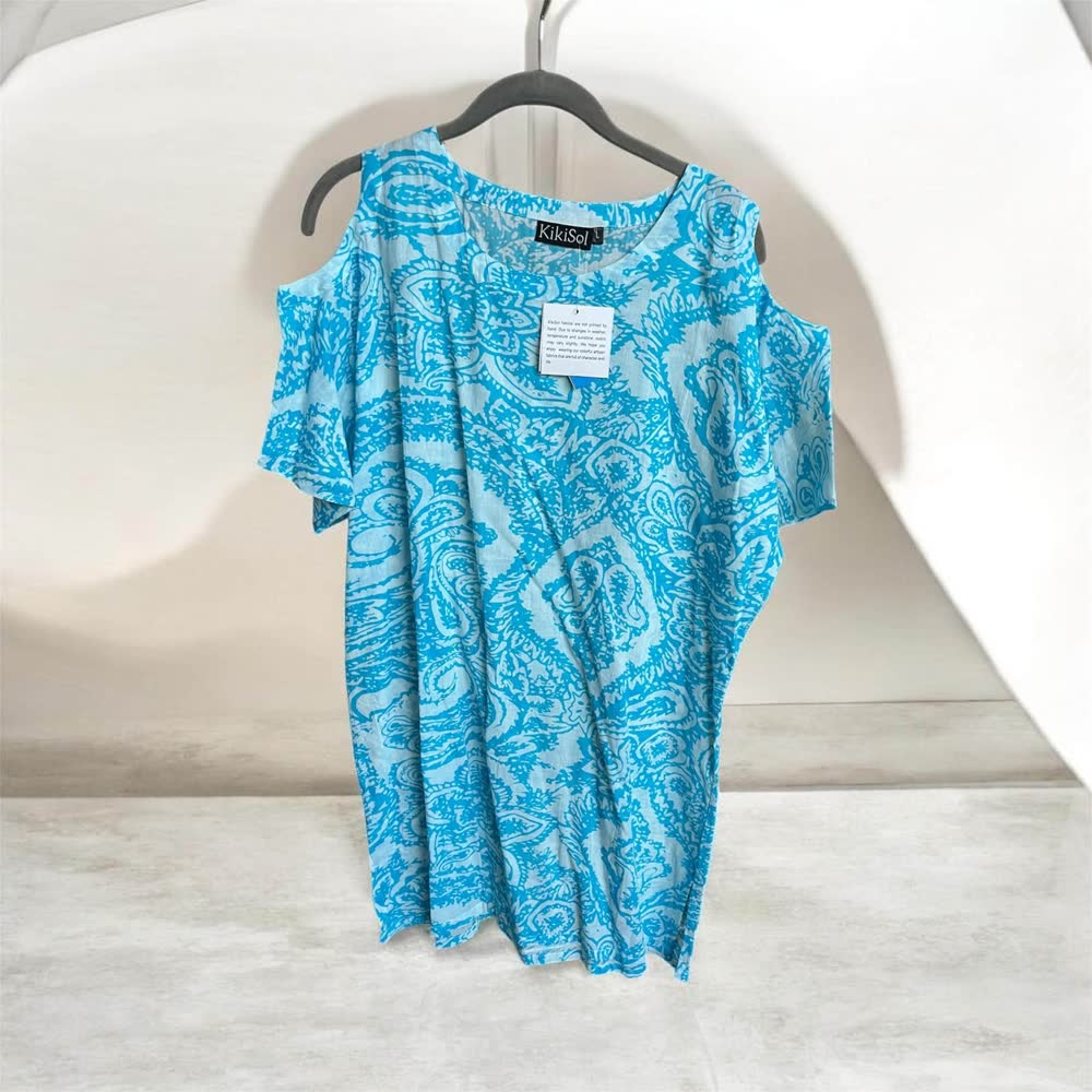 Turquoise and white paisley tunic with cold-shoulder sleeves on a hanger